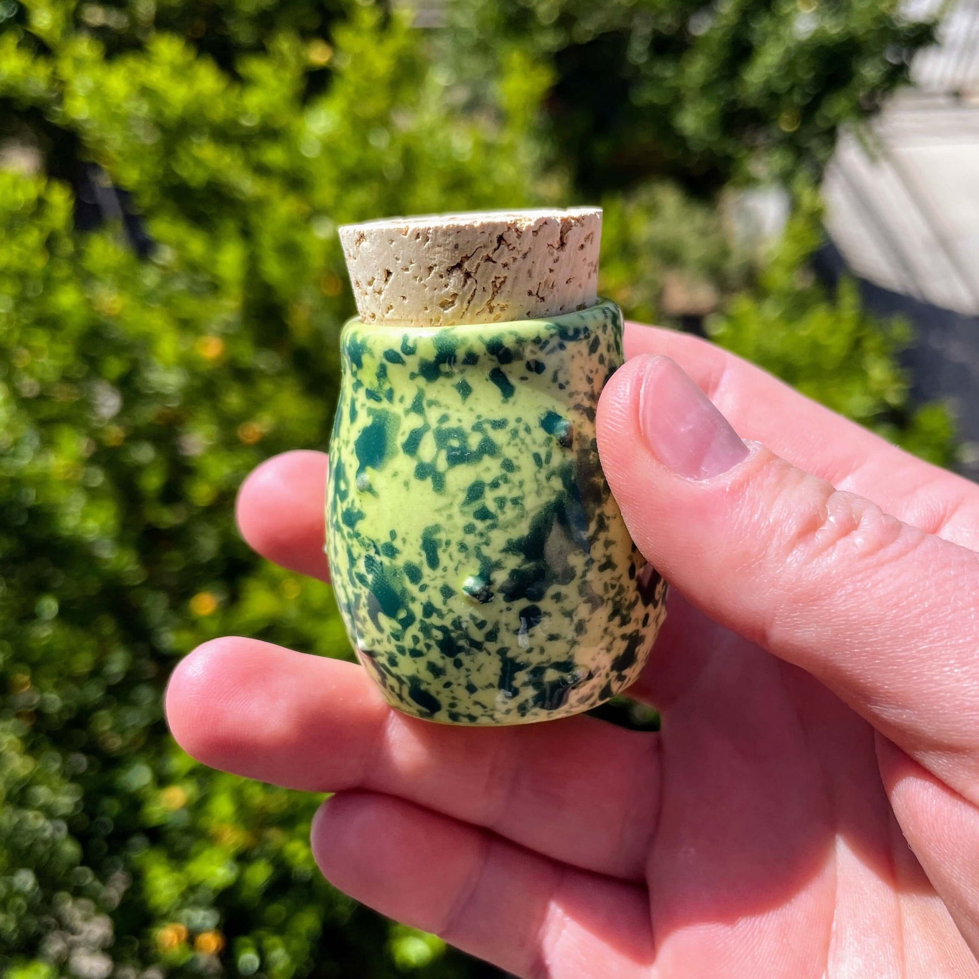 Hand holding a green and black speckled ceramic jar with a cork lid, part of a handmade eco-friendly Frog Set for stoners.