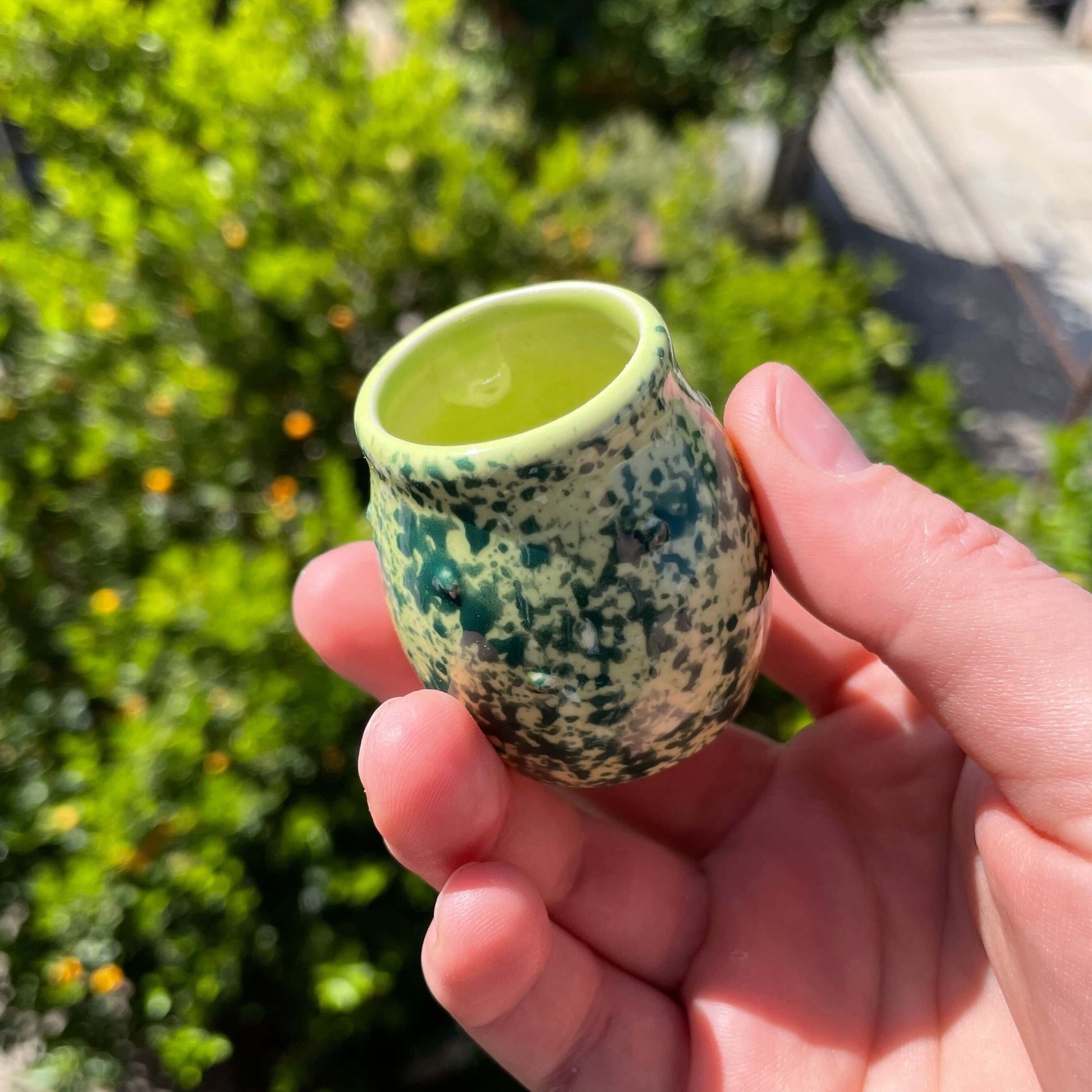 Handmade ceramic jar from Frog Set, held outdoors, showcasing its eco-friendly design and unique green pattern.